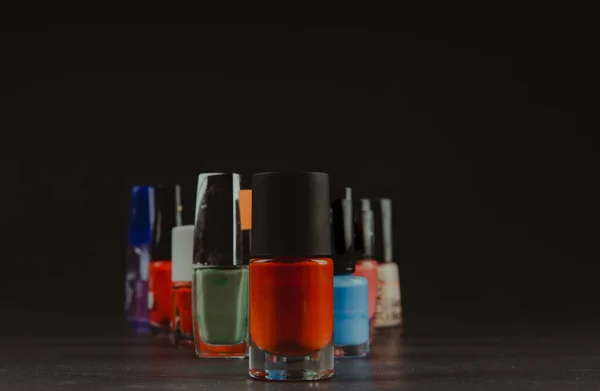 Цветной лак для ногтей бутылки на темном фоне — стоковое фото
