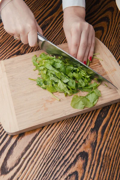 Mulher mão de corte de espinafre usando uma faca de cozinha grande afiada — Fotografia de Stock