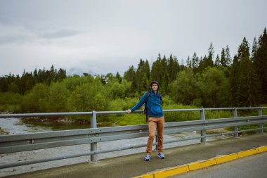 Erkek turist dağ nehrinin yanında duruyor.