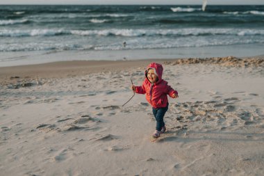 Güneşli bir kumsalda küçük sevimli bir kız. Özgün çocukluk.
