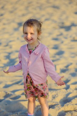 Güneşli bir kumsalda küçük sevimli bir kız. Özgün çocukluk.