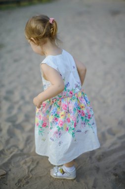 Güneşli bir kumsalda küçük sevimli bir kız. Özgün çocukluk.