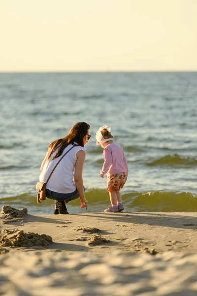 Moeder en dochtertje spelen op het strand. Authentiek beeld — Stockfoto