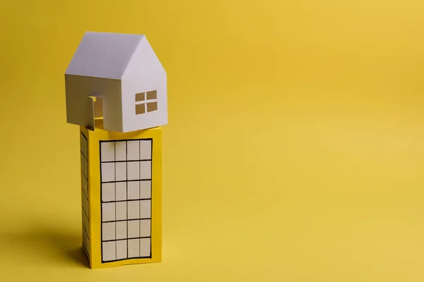 Witte familie papieren huis over blok van flats op gele achtergrond papier. Minimalistisch en eenvoudig concept, stijl. Begrepen, ruimte. Horizontale oriëntatie. — Stockfoto