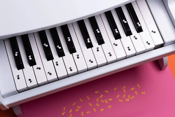 white toy piano with paper notes. music piano concept. view from above