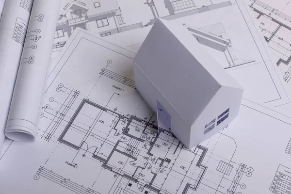 White family paper house, house projects plan and blueprints in the background. Minimalistic and simple concept, style. Horizontal orientation. — ストック写真