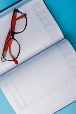 Fotokopi alanı ve ofis malzemeleriyle iş planlaması. Mavi arkaplanda kırmızı gözlük