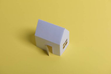 Beyaz aile gazetesi, sarı arka plan kağıdına erkek eli kondu. Minimalist stil. Uzayı kopyala Yukarıdan bak. Dikey yönelim