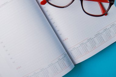 Fotokopi alanı ve ofis malzemeleriyle iş planlaması. Mavi arkaplanda kırmızı gözlük