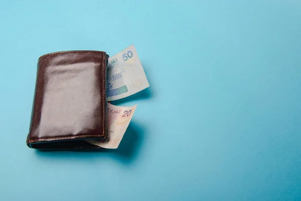 stock image brown mans leather wallet with money bills on a blue background