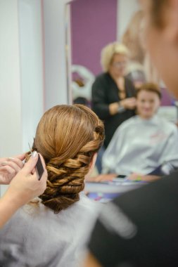 Genç ve güzel gelin, profesyonel makyözün düğün makyajını yapıyor..
