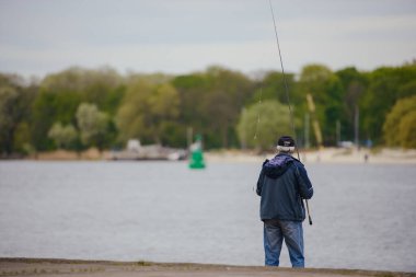 Genç adam gün batımında tekneyle gölde balık tutuyor..