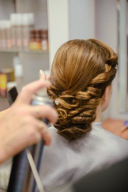 Genç ve güzel gelin, profesyonel makyözün düğün makyajını yapıyor..