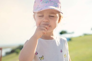 Çayırda gülümseyen kız kameraya bakıyor.