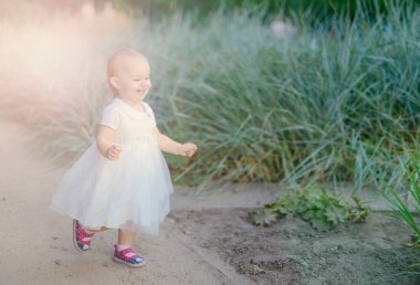 Çayırda gülümseyen kız kameraya bakıyor.