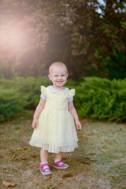 Çayırda gülümseyen kız kameraya bakıyor.