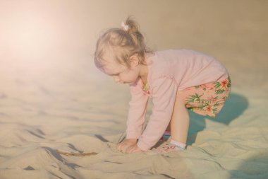 Güneşli bir kumsalda küçük sevimli bir kız. Özgün çocukluk