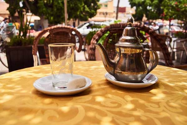 A glass and a traditional tea pot on a table in Morocco