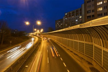 Poznan 'da bir gece boyunca apartman blokları ve iki şeritli bir sokak.