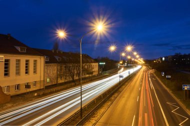 Poznan 'da bir gece boyunca apartman blokları ve iki şeritli bir sokak.