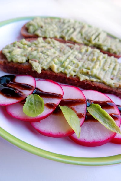 sliced radish and guacamole toasts on plate