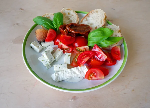 goat cheese, tomato, fresh basil and white bread on white plate