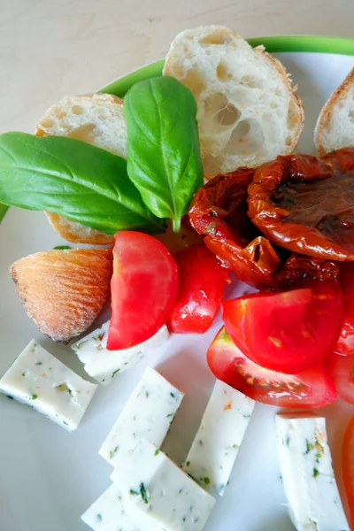 goat cheese, tomato, fresh basil and white bread on white plate