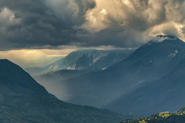 Rain in the mountains. Socha valley, Slovenia. Dramatic shot of heavy storm clouds, green meadows, and fog on the mountains