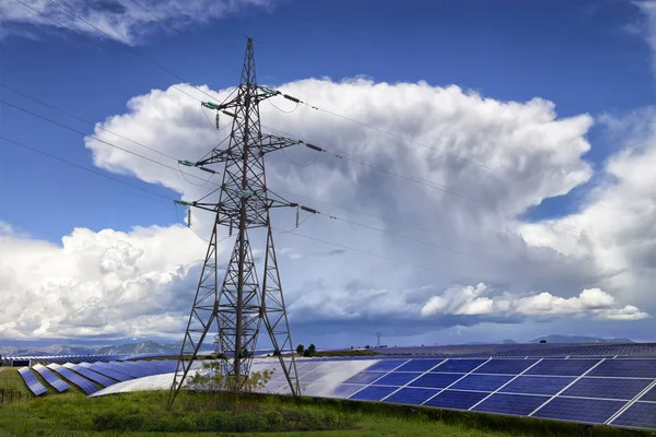 人と自然のエネルギー 太陽電池パネルと高圧送電線 背景に大きな雷雨とフィールド — ストック写真