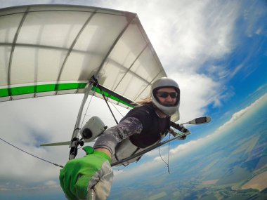Brave hang glider pilot takes selfie while flying high above ground. Unusual shot of extreme sport with action camera. clipart