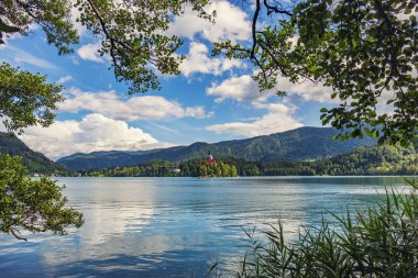 Mavi berrak suları yeşil ağaçlar tarafından çerçeveli Bled Gölü