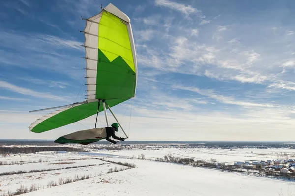 悬挂滑翔机飞行员在他的绿色五颜六色的翅膀上飞行 — 图库照片