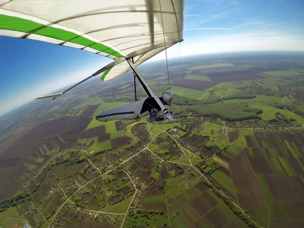 Летчик-дельтаплан летит высоко над зелеными весенними полями — стоковое фото