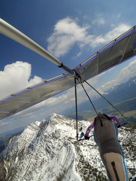 Coraggioso pilota volare sopra la vetta della montagna cobered da neve su un hang gli — Foto Stock