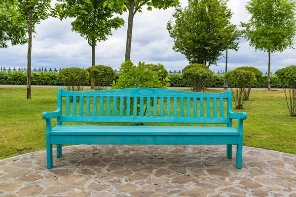 Krásná prázdná modrá dřevěná lavička v parku. — Stock fotografie