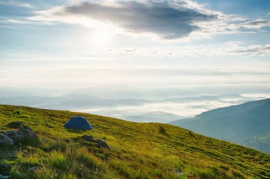 Dağların tepesinde, sisli vadide güzel panoramik manzaralı yalnız bir turist çadırı.