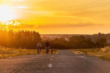 2020-07-15 Bucha, Ukrayna. Mutlu orta yaşlı çift köpekleriyle bisiklete biniyor. Yaz tatili