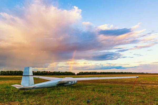 Plane on the airfield with beautiful cloud and rainbow. Sailplane or glider at the airfield is waiting for the adventure.