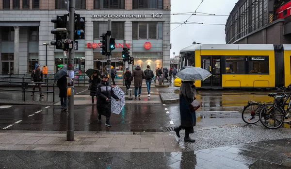 Pasajeros y peatones en Berlín friedrichstrasse en tiempo lluvioso, Alemania — Foto de Stock