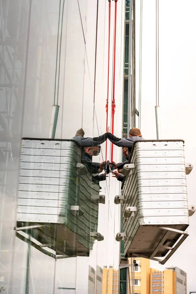 Handwerker stehen in einem Korb und erneuern die Glasscheibe eines Bürokomplexes in der Berliner Innenstadt — Stockfoto