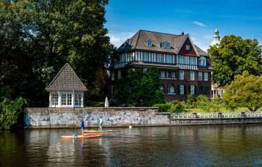 Pedallı botlar, Almanya 'nın Winterhude kentindeki asil Hamburg yerleşim alanındaki Alster' da kürekçiler, kanolar ve vapurlar ayağa kalksın.