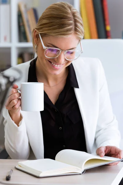 Tiro Bela Jovem Empresária Bebendo Café Rever Seu Diário Escritório — Fotografia de Stock