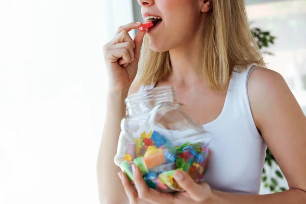 カラフルなゼリーを食べるのはかなり若い女性のクローズ アップは家でお菓子します 中毒の概念 — ストック写真