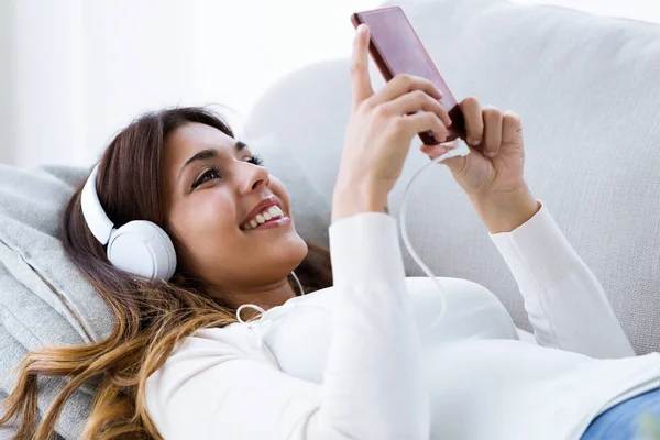 Фотография Красивой Молодой Женщины Использующей Мобильный Телефон Слушающей Музыку Дома — стоковое фото