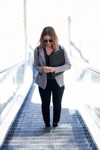機械式の階段で彼女の携帯電話を使用してかなり若いビジネス女性のショット — ストック写真