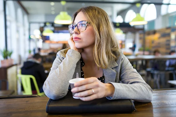 カフェでコーヒーを飲みながら横に探しているかなり若い女性のショット — ストック写真