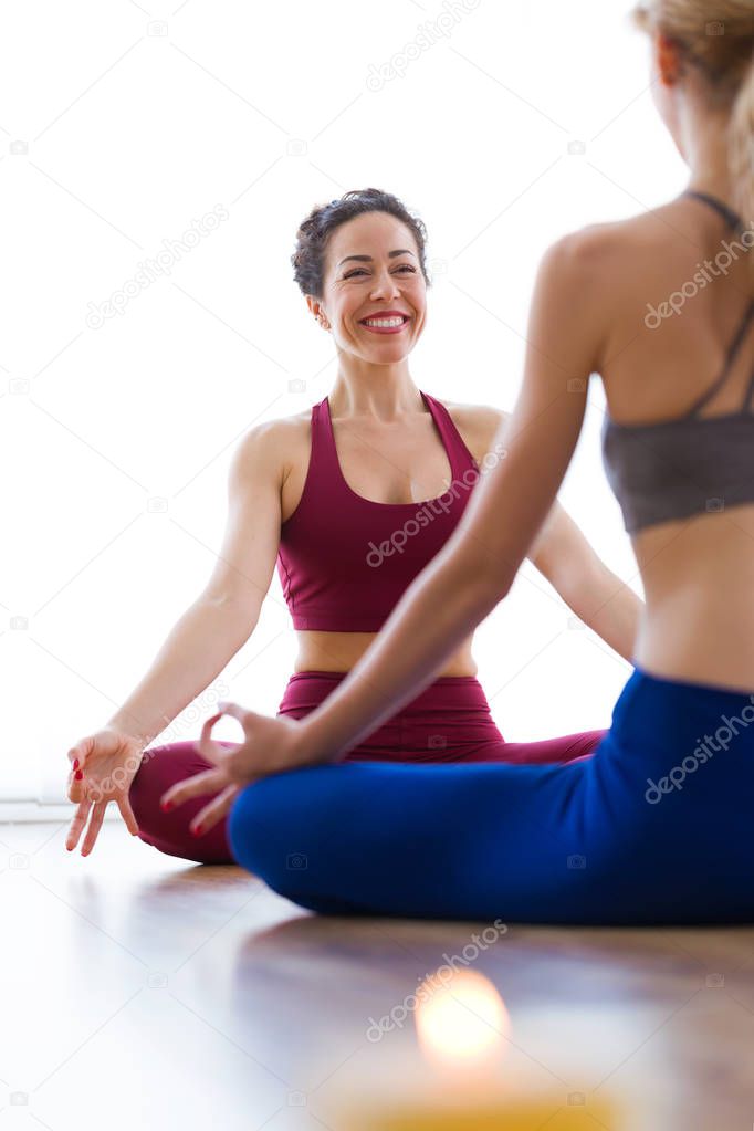 Shot of two pretty young women practicing yoga at home. Lotus position.