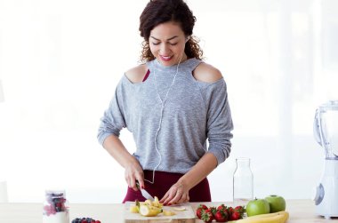 Genç ve güzel kadın kesme muz mutfak müzik dinlerken kadeh.