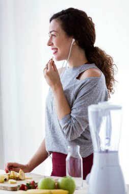 Genç ve güzel kadın mutfakta müzik dinlerken muz yemek kadeh.