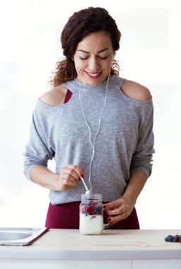 Genç ve güzel kadın beyaz arka plan üzerinde kırmızı meyve ile yoğurt hazırlanması kadeh.